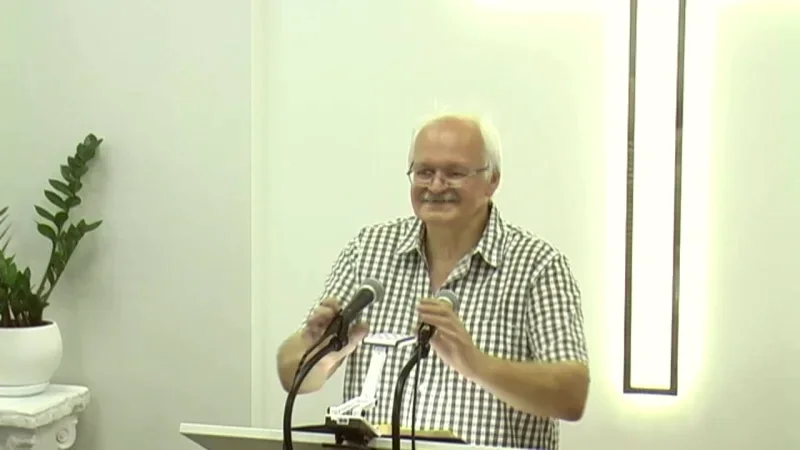 Чоловік у картатій сорочці говорить біля кафедри